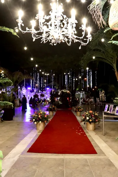 Pasillo de ceremonia con alfombra roja, candelabros y arreglos de flores tropicales