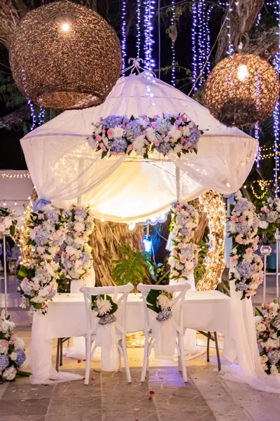 Altar de ceremonia con cortinas de luces, lámparas colgantes y flores blancas