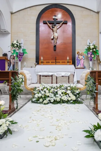 Pasillo de iglesia con arreglos de flores blancas en las bancas
