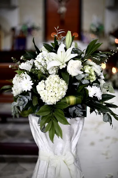 Arreglo blanco de lirios, hortensias y follaje sobre un pedestal con tela